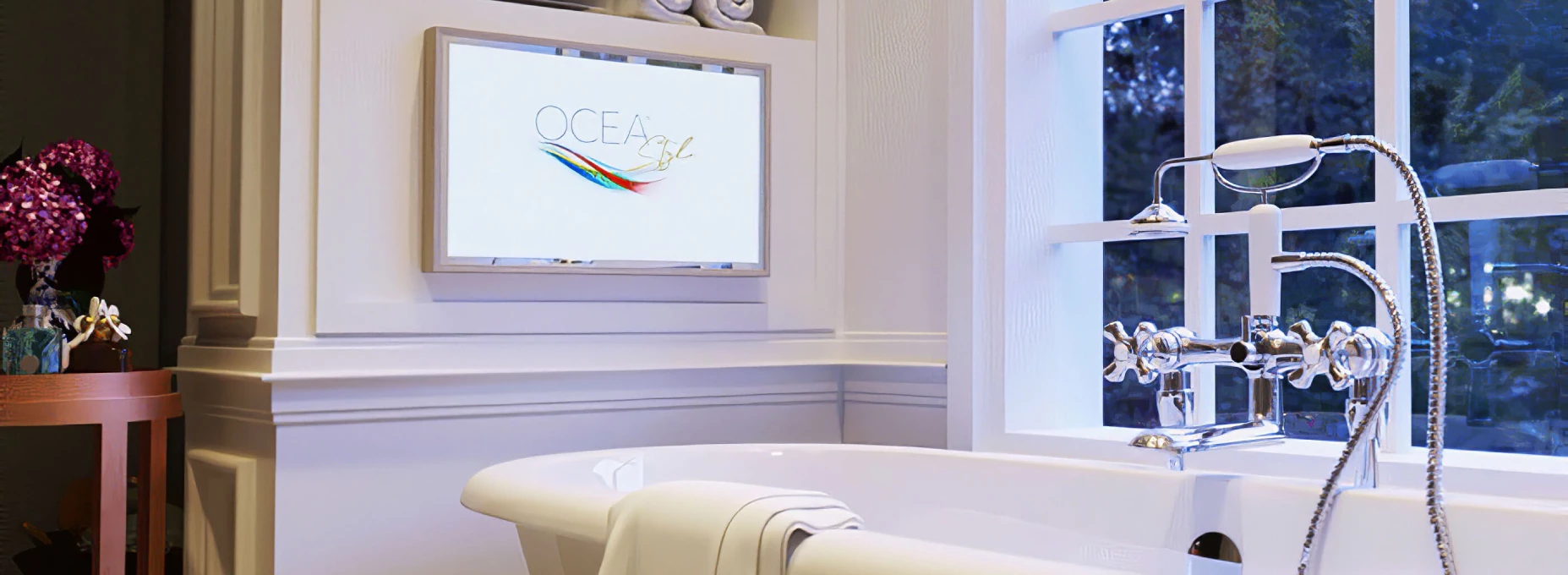 Above a neutral bathtub with a glass pane is an Ocea bathroom TV with a white frame in Kuwait.